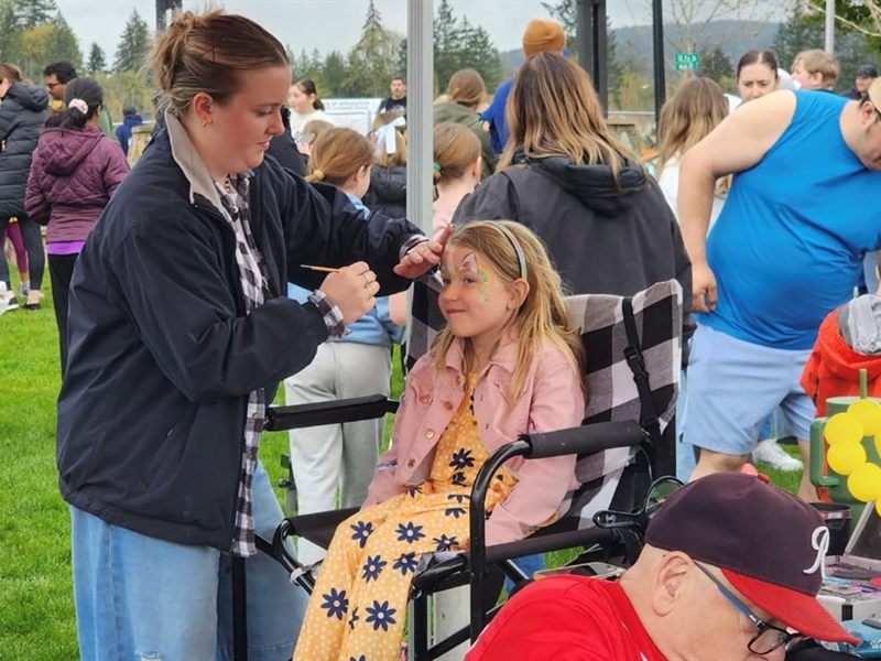 Artist painting a girl's face at an outdoor event