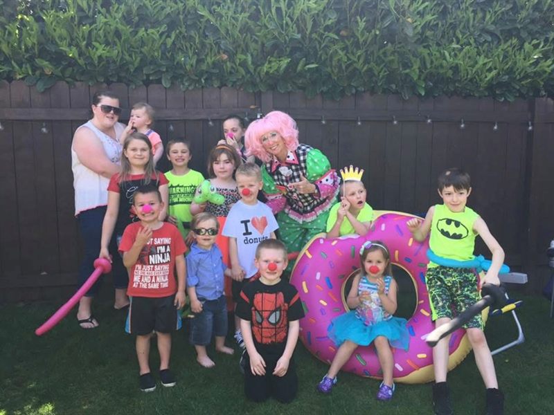 Clown posing with a group of children and a doughnut inflatable