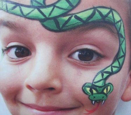 Boy smiling with a green snake face painting