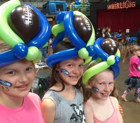 Three girls wearing balloon football hats